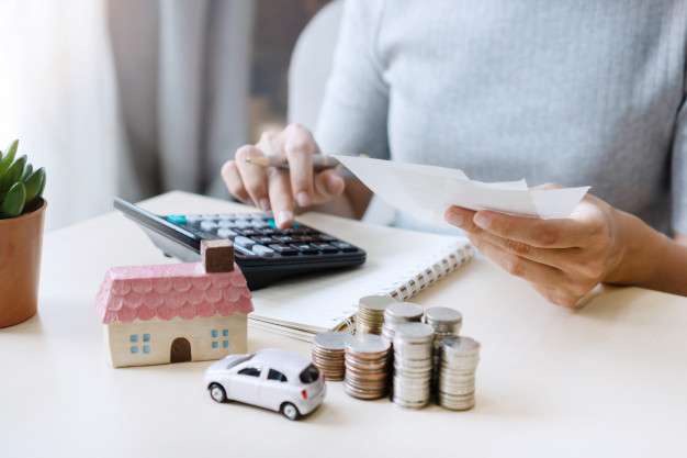 businessimages_close-up-hand-holding-bills-while-using-calculator-stack-coins-toy-house-car-table-saving-future-manage-success-business-finance-concept_164138-728